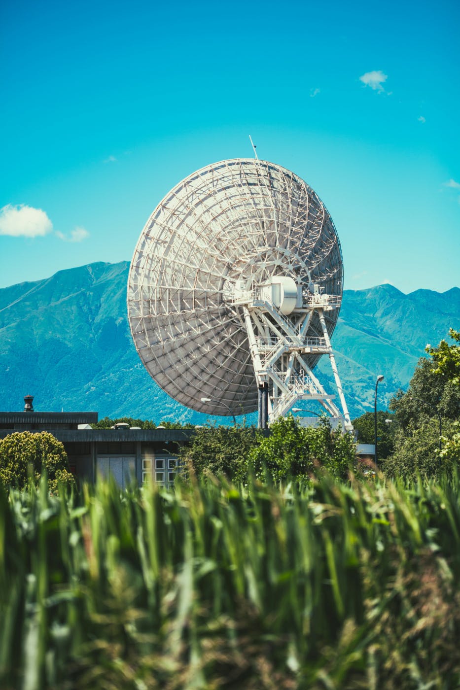 A giant satellite dish in a field in front of mountains