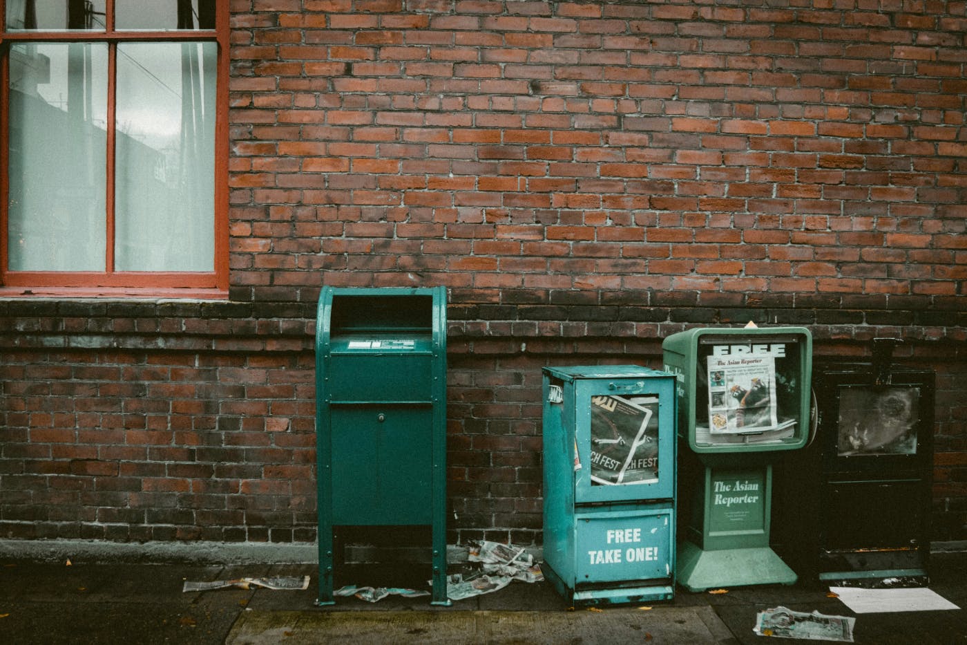 A mail box and two destroyed newspaper boxes in all alley