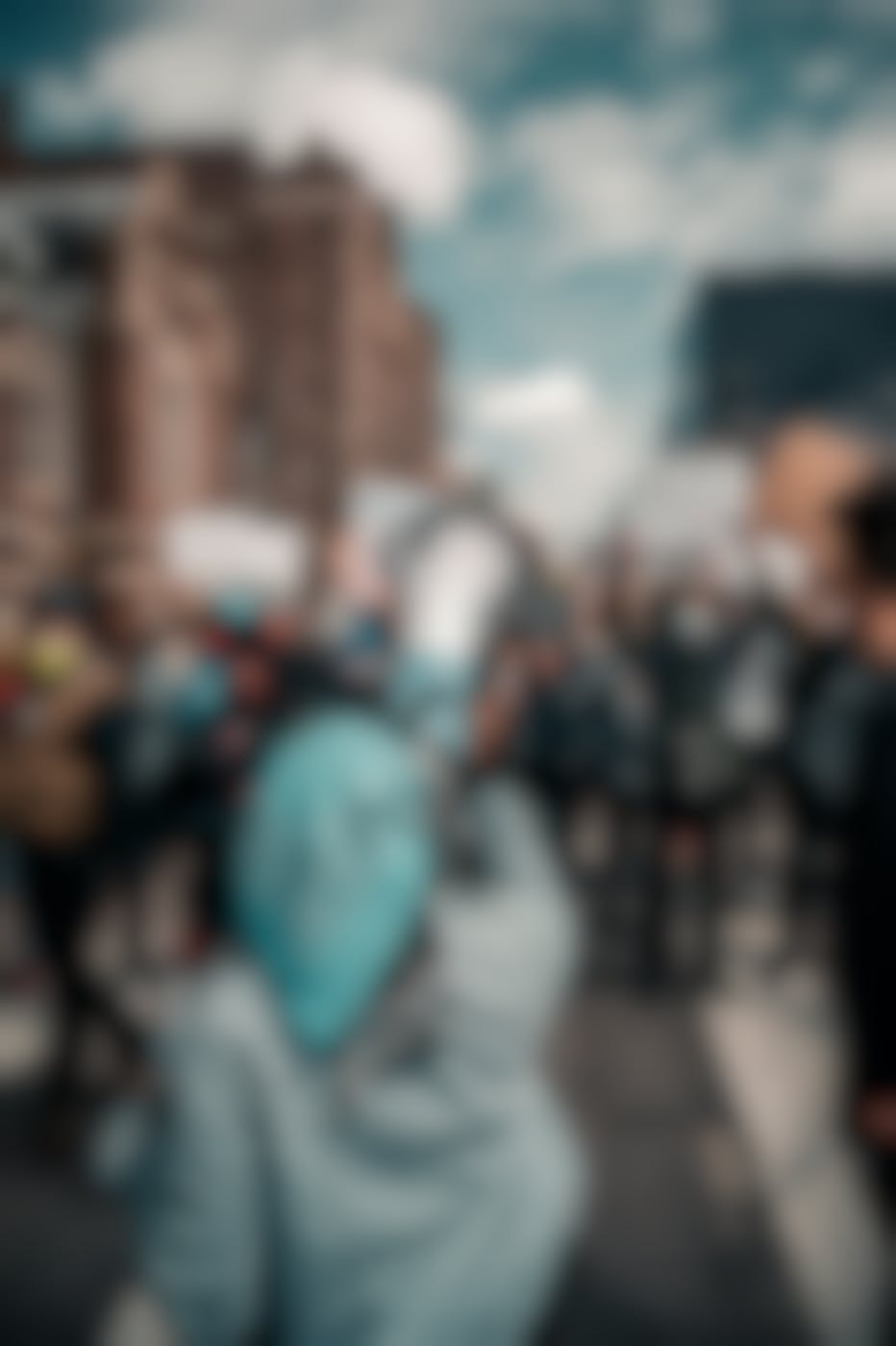 A girl with beaded hair holding a megaphone addressing a crowded street in protest