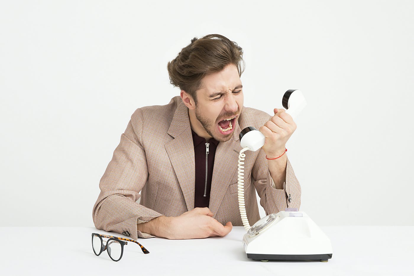 A well dressed man screaming into a landline phone