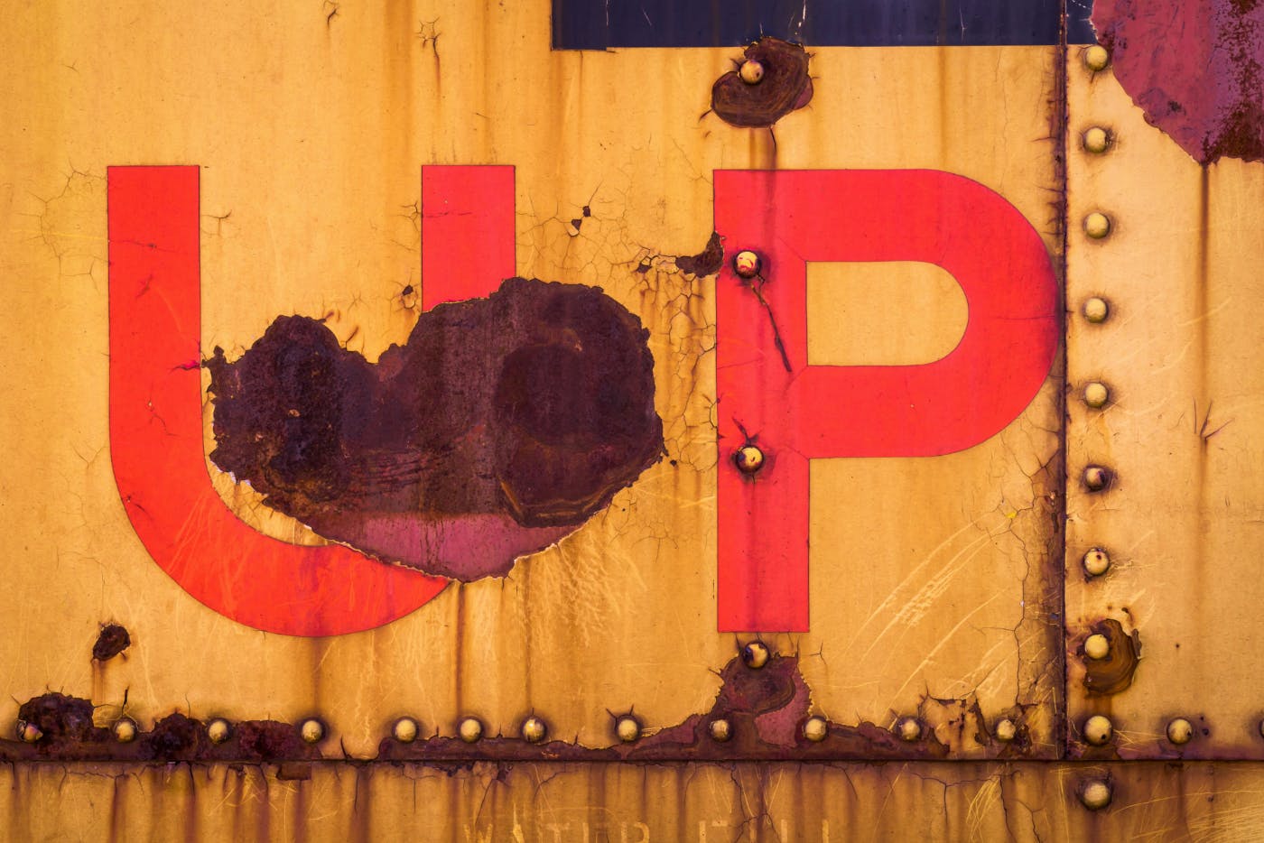 The word UP painted on the side of a worn shipping container