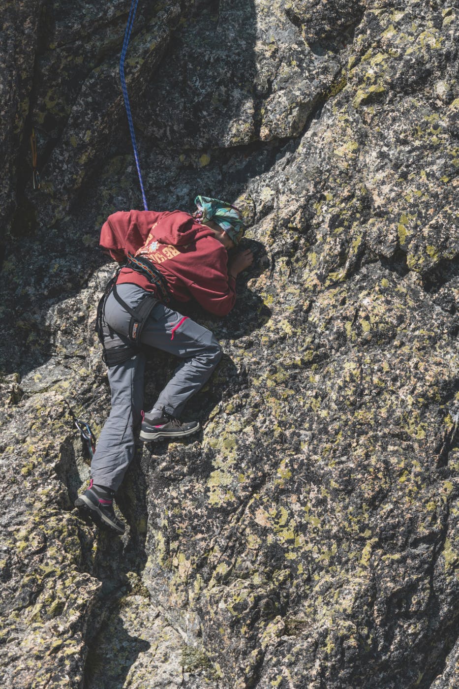 A person in climbing gear struggling up a rock face