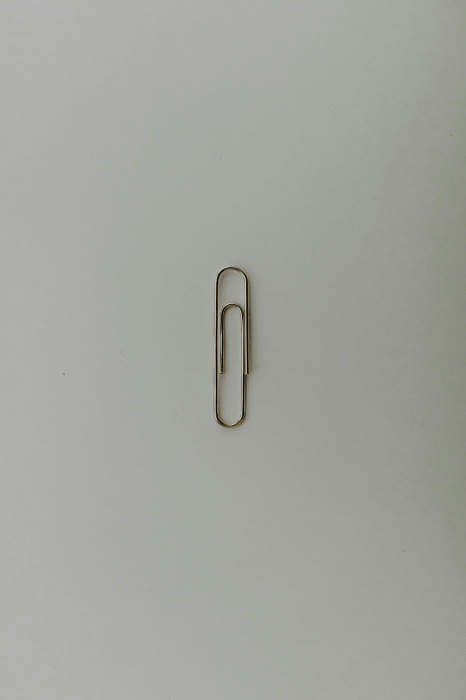 A single paper clip on  a gray background