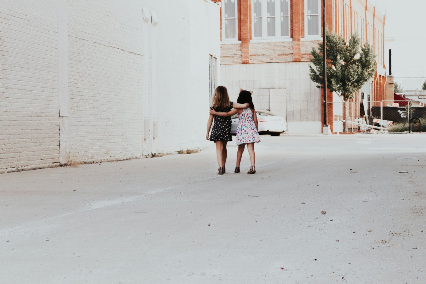 Two little girls arm and arm in a blighted neighborhood