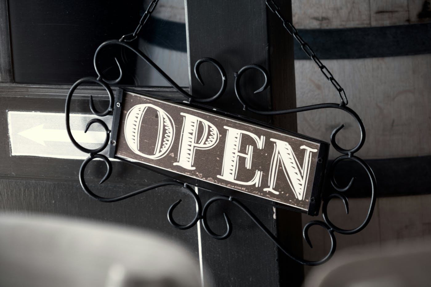 An ornate metal sign with the word open written in chalk