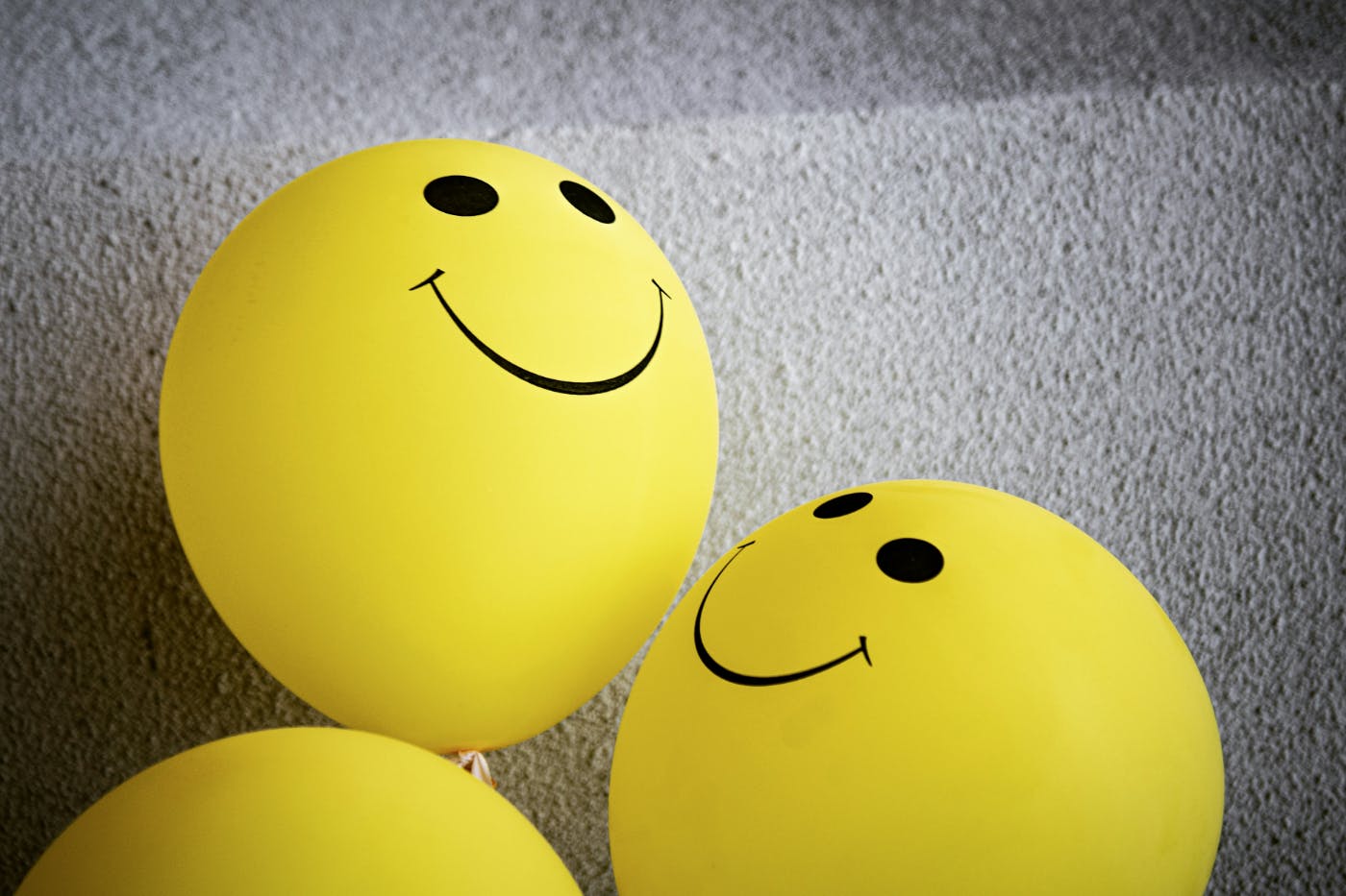 Two and a third yellow smiley face balloons