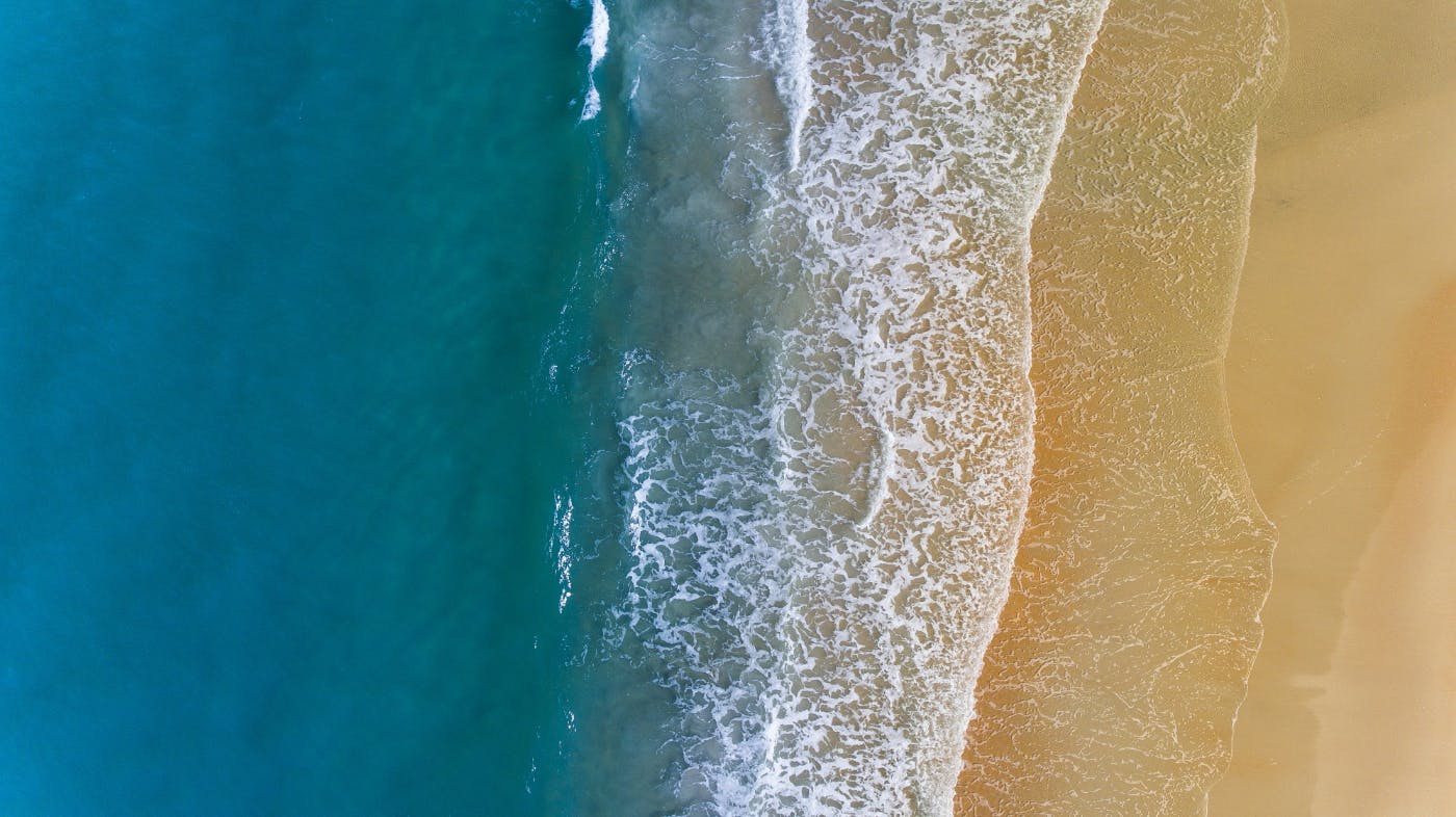 Aerial view of the beach transitioning into the ocean