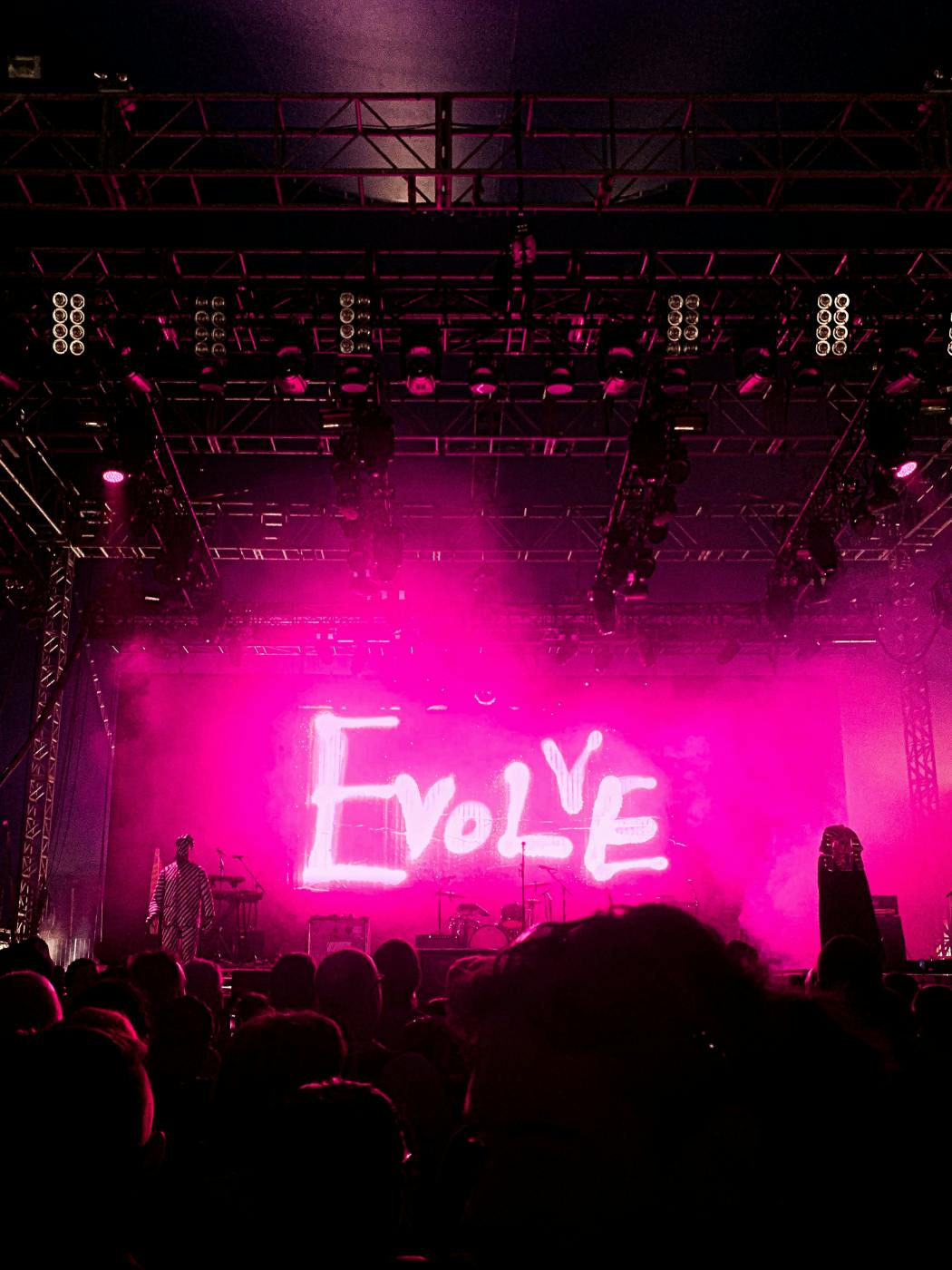 a stage with a large pink neon sign reading evolve