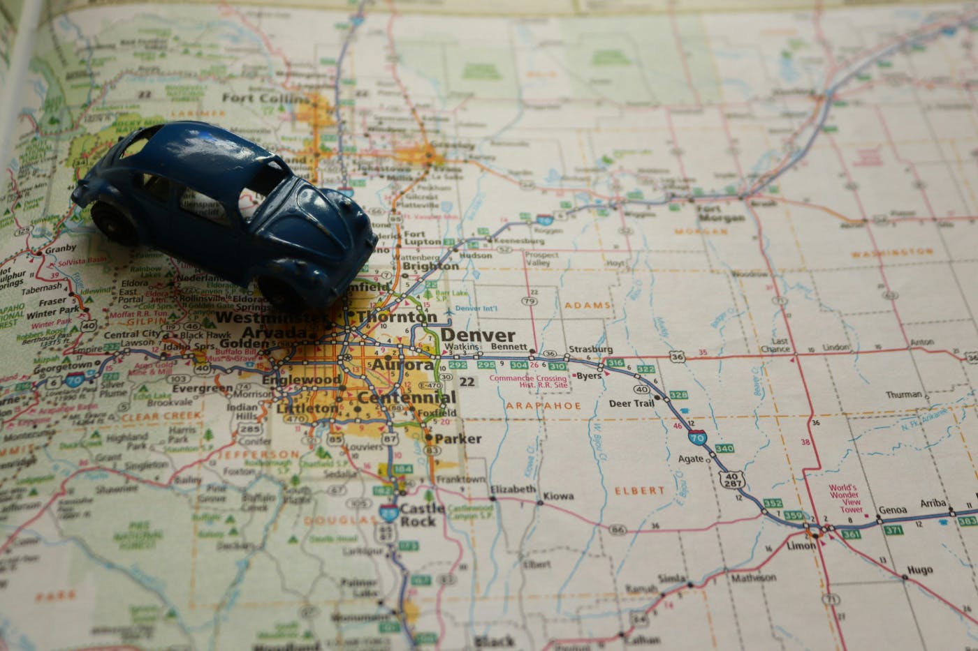 a blue toy VW Beetle sitting on a road map near Denver