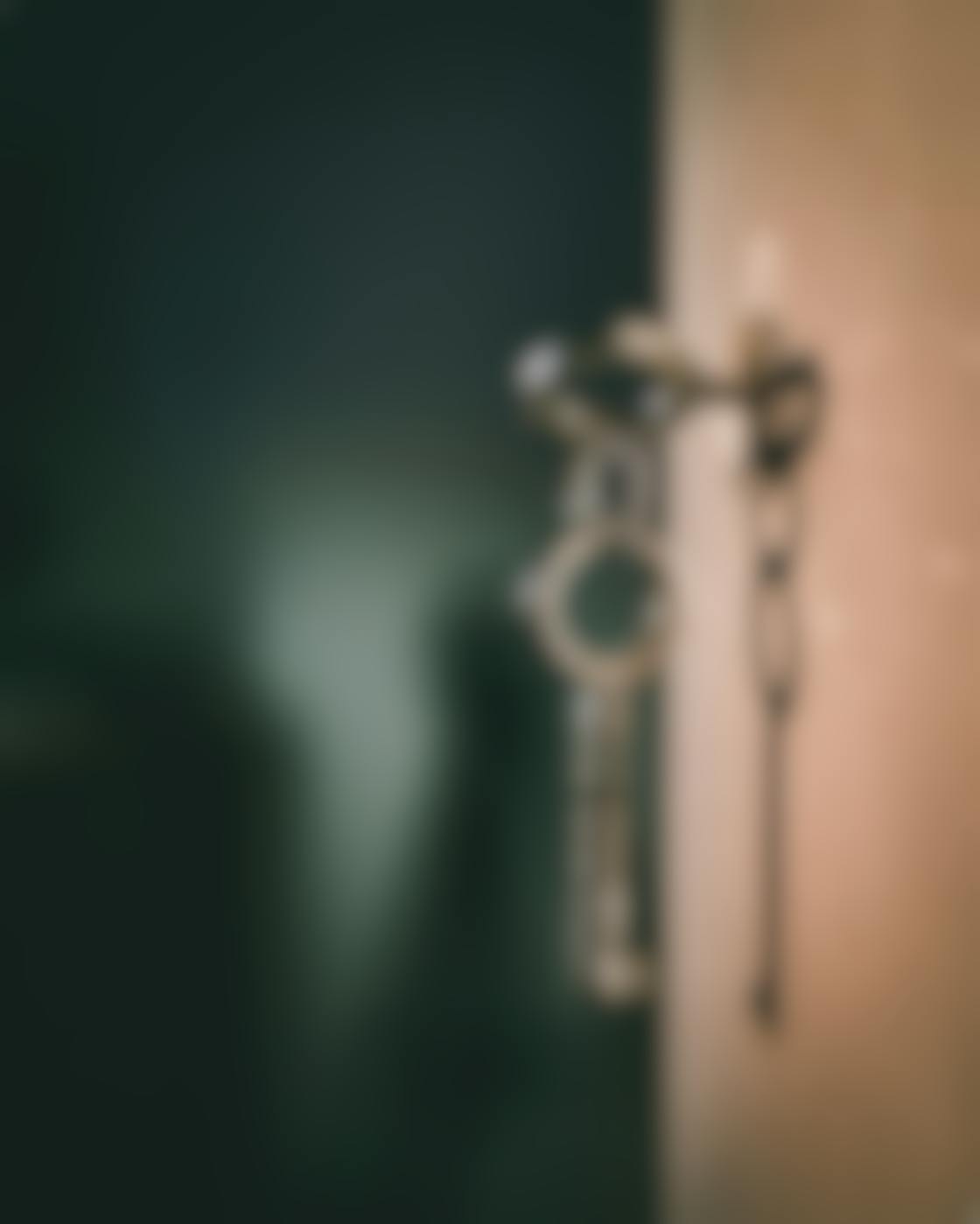 A skeleton key in a  lock with another dangling from it with the key's shadow on the wall