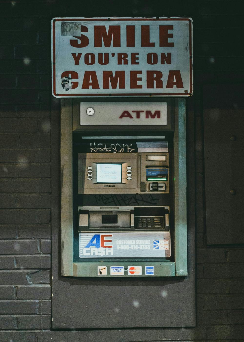 An ATM with a sign over it reading, "Smile You're On Camera"