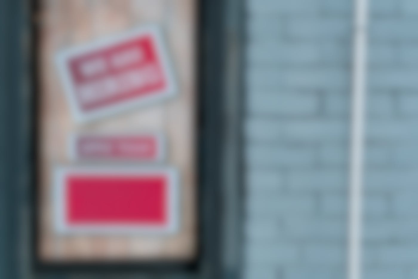 A borded up window with two red signs; We Are Hiring & Apply Today