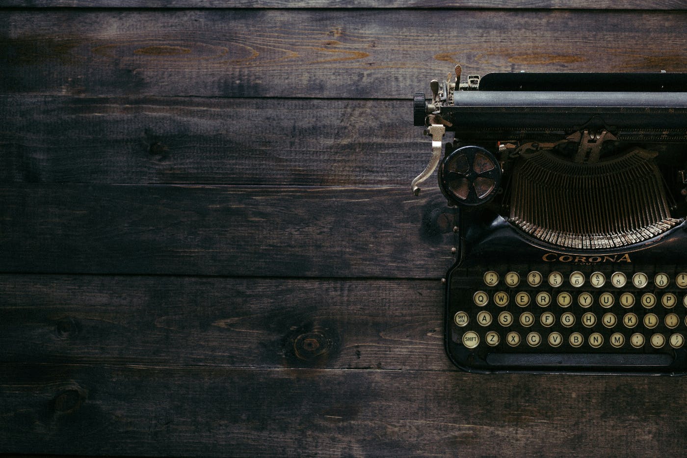 An old fashioned typewriter, sitting to the right of the frame, on a wood table