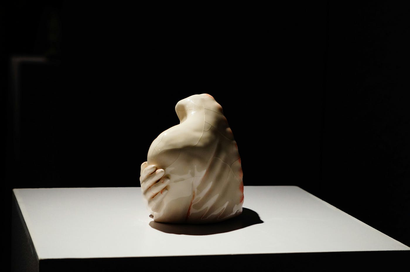 A White sculptor symbolizing and embrace on a white table with black background