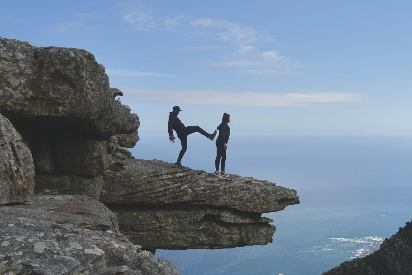 A man and woman on a cliff, the man is about to kick the woman off.