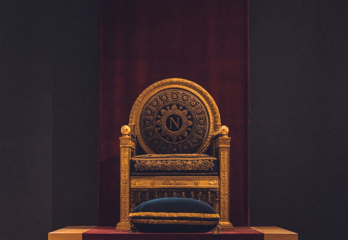 A gold throne with a blue foot pillow