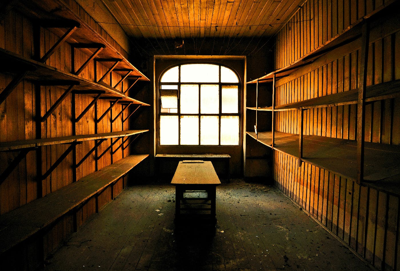 An empty room, wood walls, empty shelves and wood table and a window
