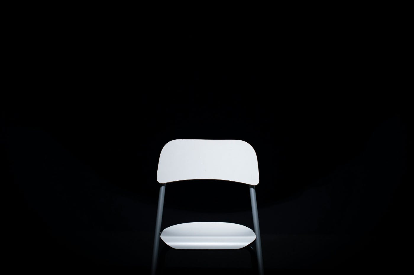An empty white chair in a black background