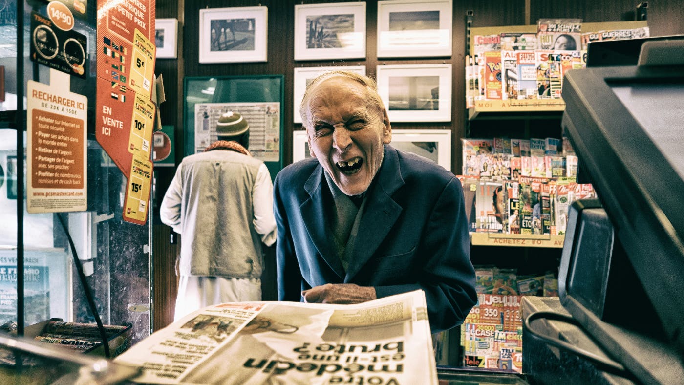 An old man at a bodega buying a newspaper