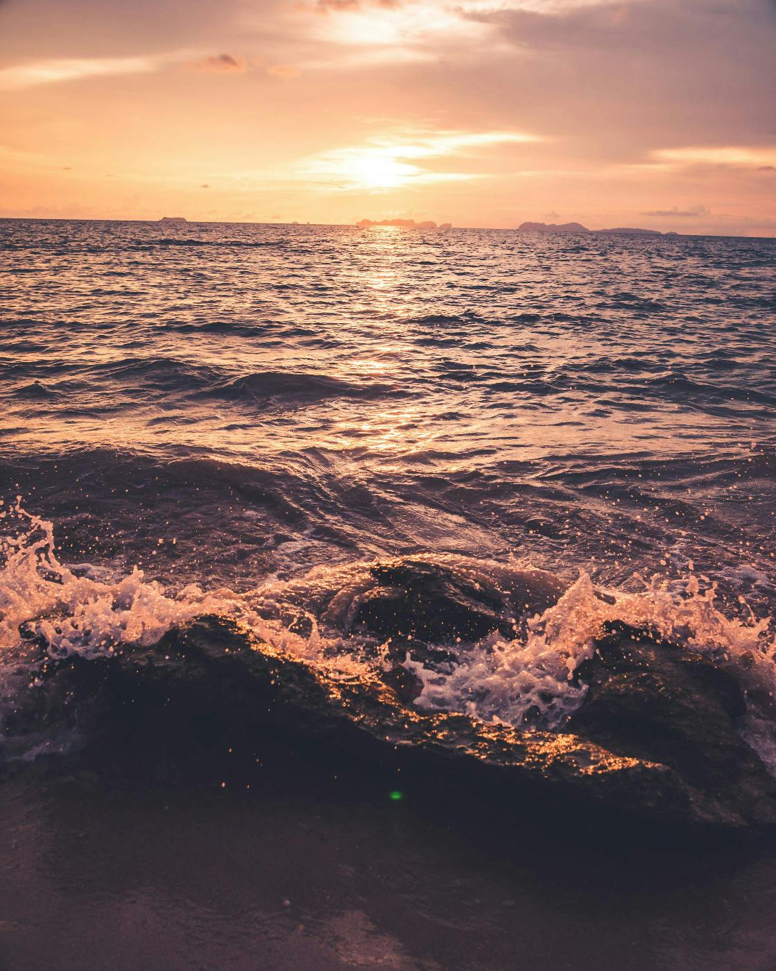 The ocean at sunset breaking on rocks