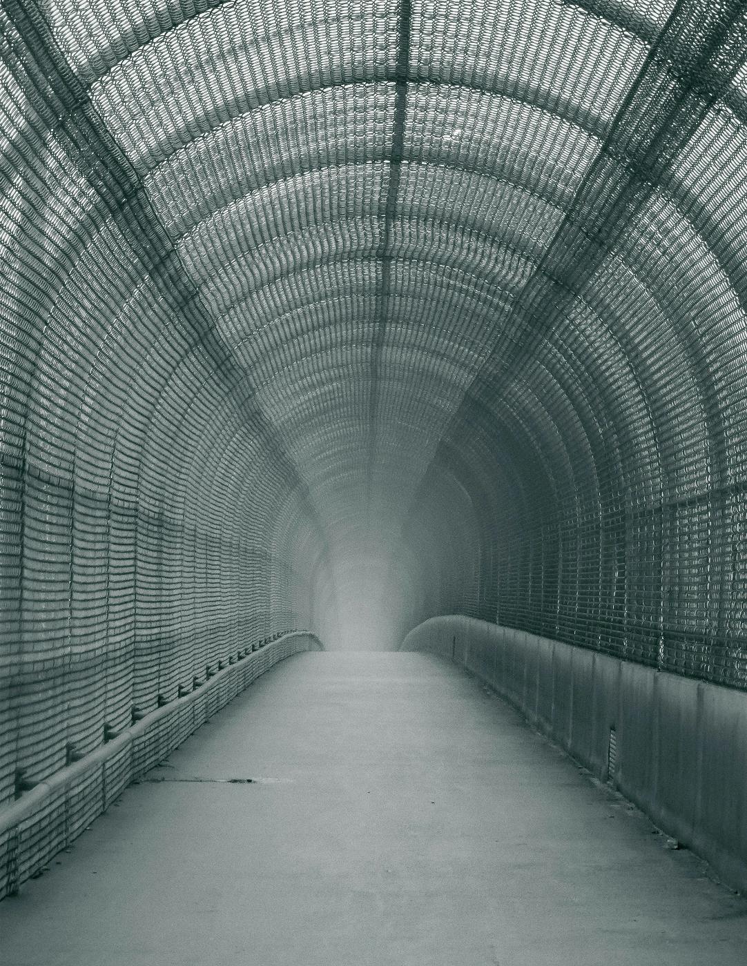 A pedestrian bridge covered by a chain link fence