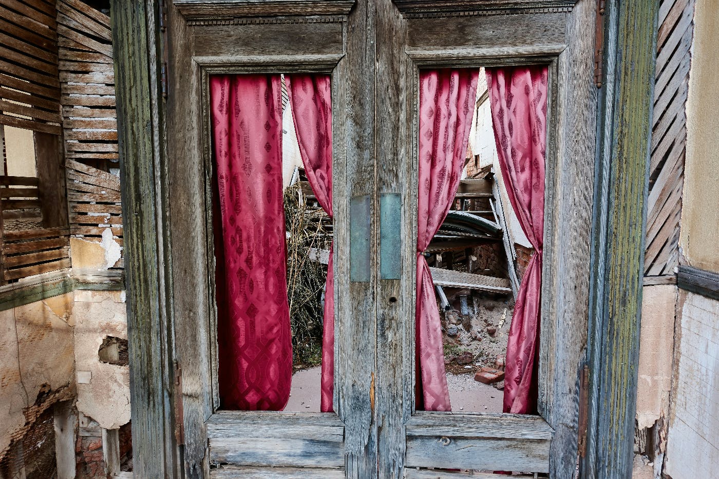 Interior of a crumbling house with red curtains on the windows