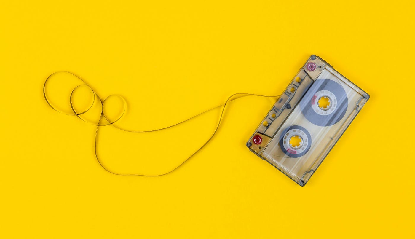 A partially unspoiled cassette tape on a yellow background
