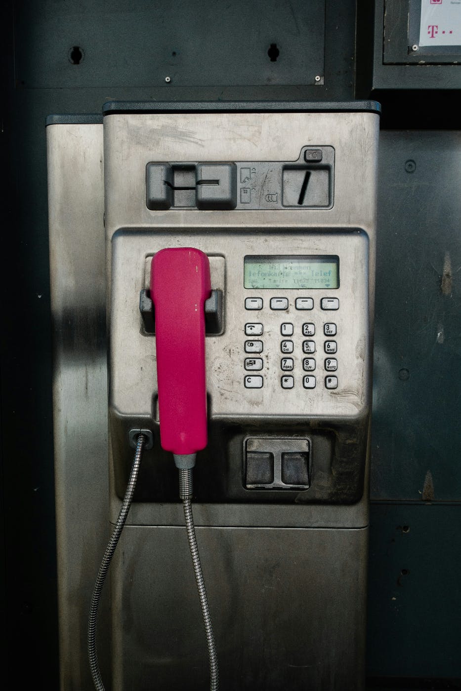 A payphone with a pink handset