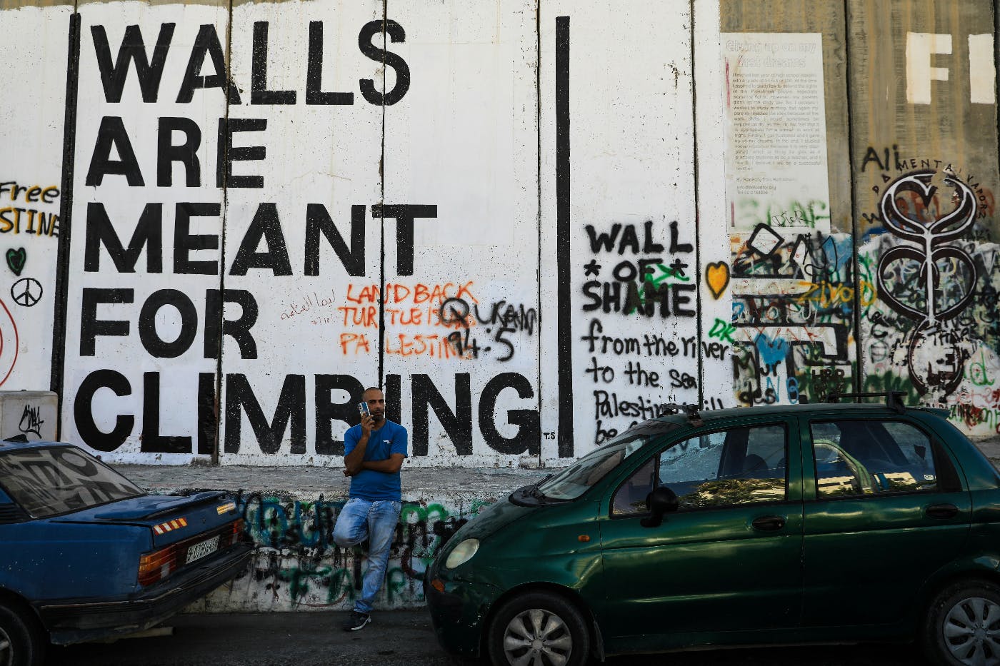 A heavily graffitied wall with the phrase Walls Are Meant For Climbing prominent