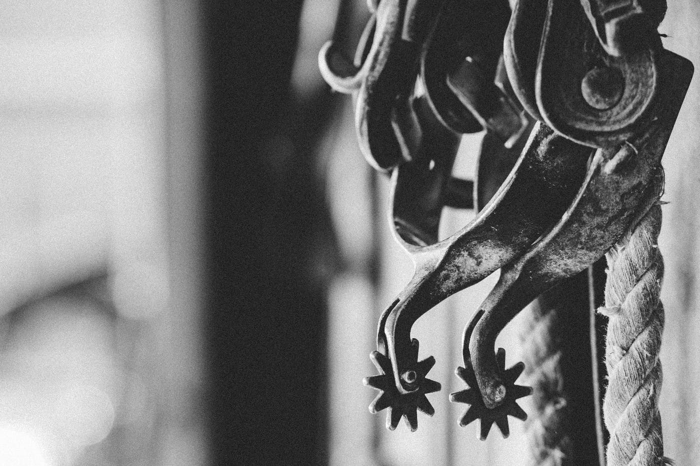 grey scale image of a pair of spurs hanging on a rope