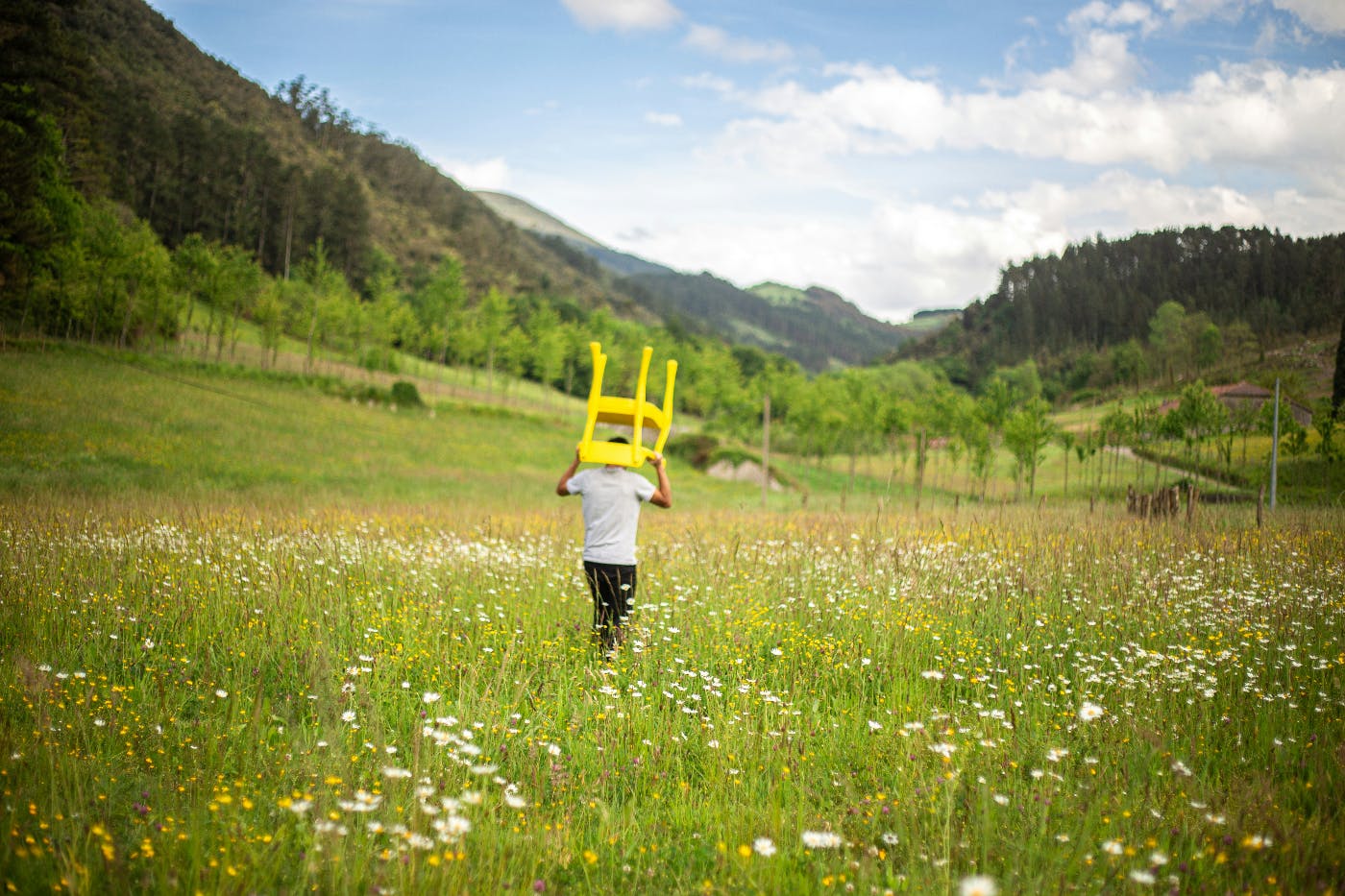 A man carrying a yellow chair into an open field