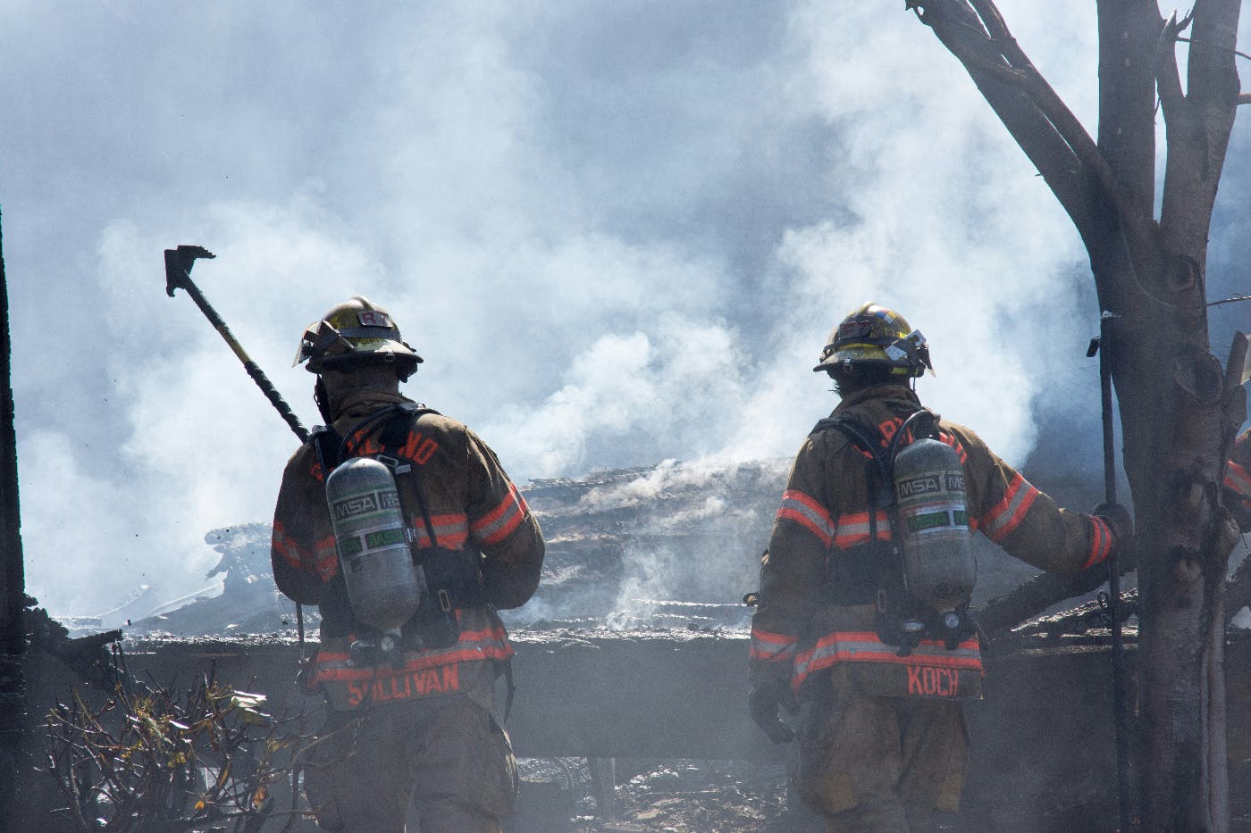 Two fire fighters standing amongst smoldering wreckage