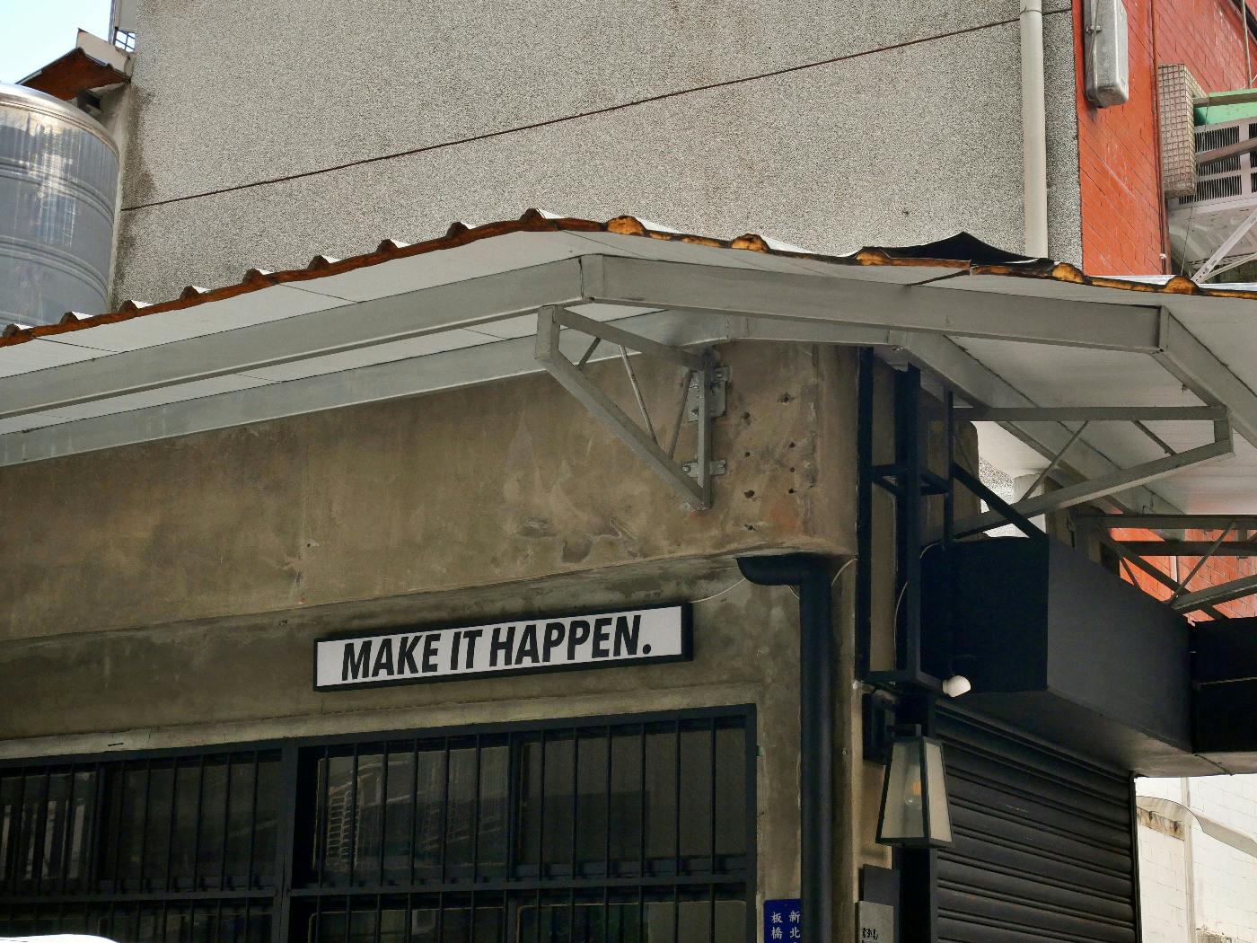 A sign on the side of a building reading make it happen