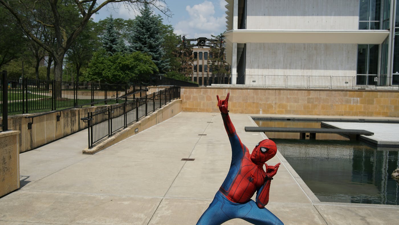 A guy outside a government building wearing a Spider-man costume and posing