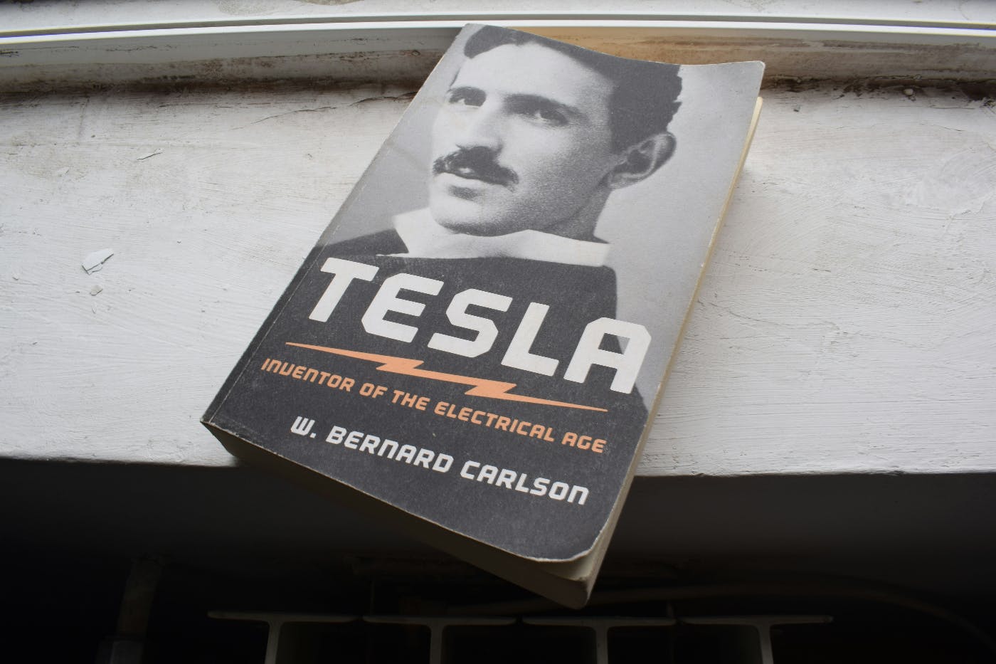 A worn copy of W. Bernard Carlson's book Tesla, Inventor of the Electrical Age, sitting on a window sill