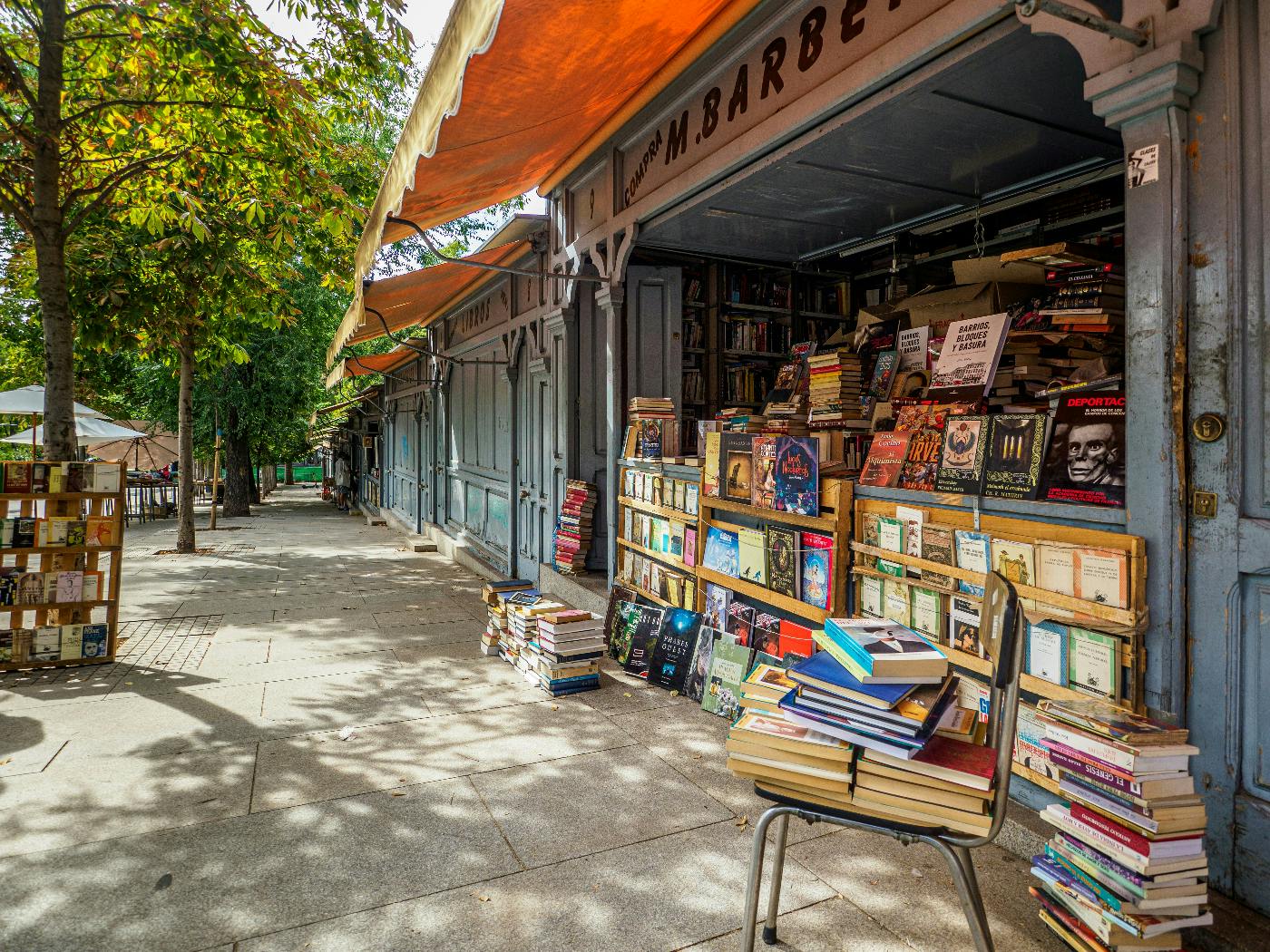 A bookstore with a garage style door open and shelves on the sidewalk