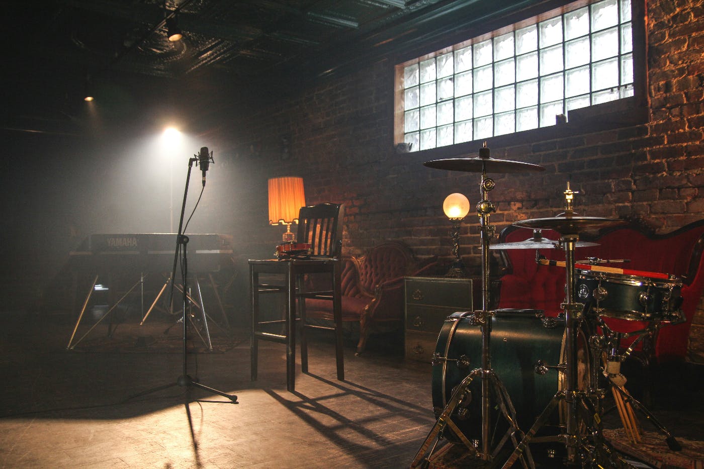 Interior, exposed brick music room with drums, mic, electric piano and a violin on a chair.