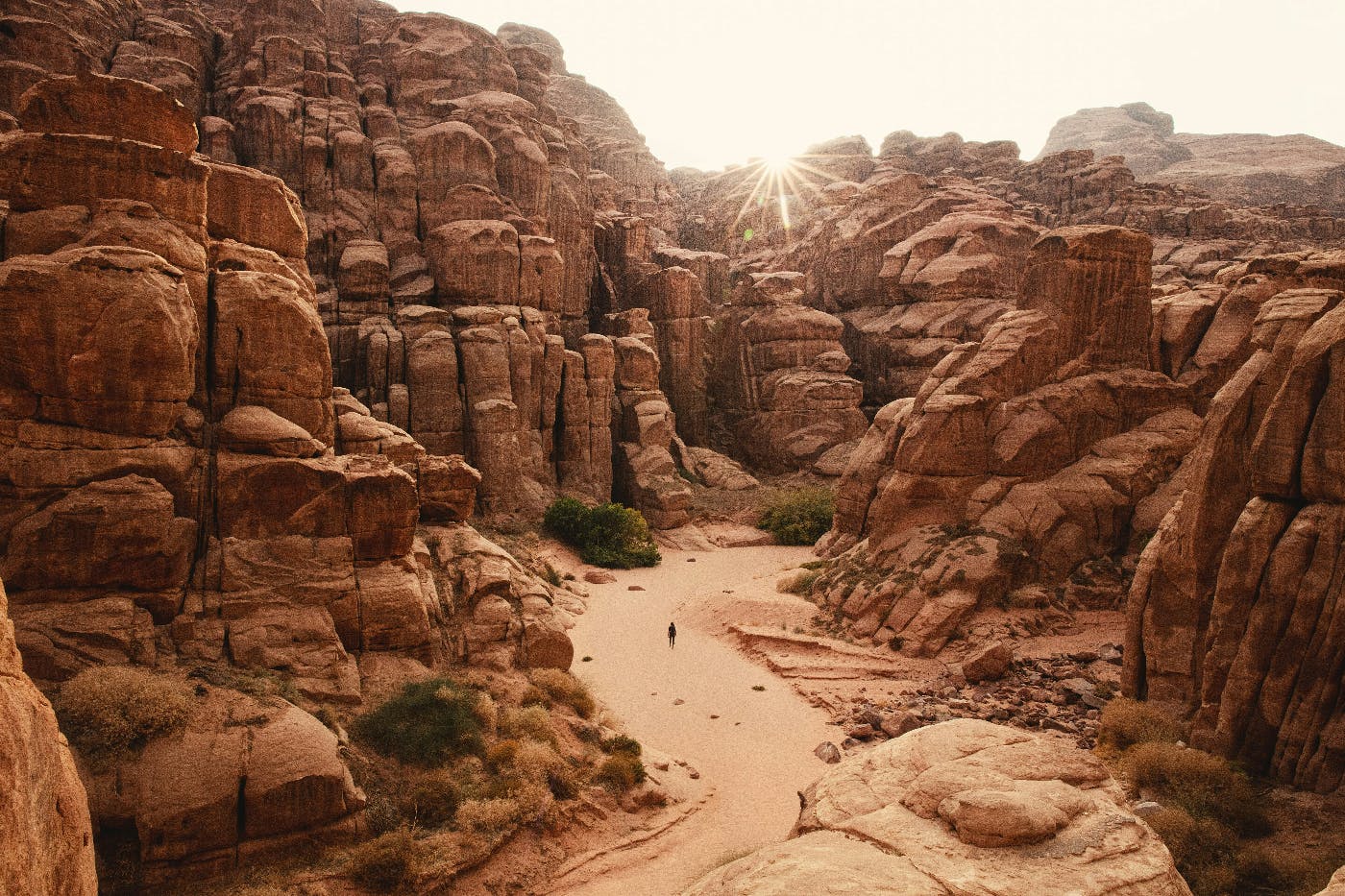 A person walking a sand path through a canyon