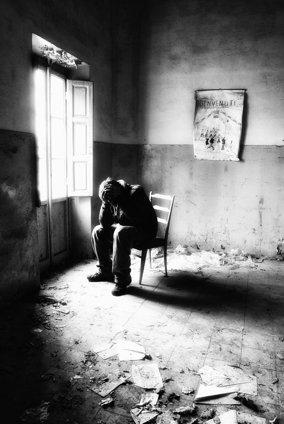 A black and white image of a man in a chair in a demolished room