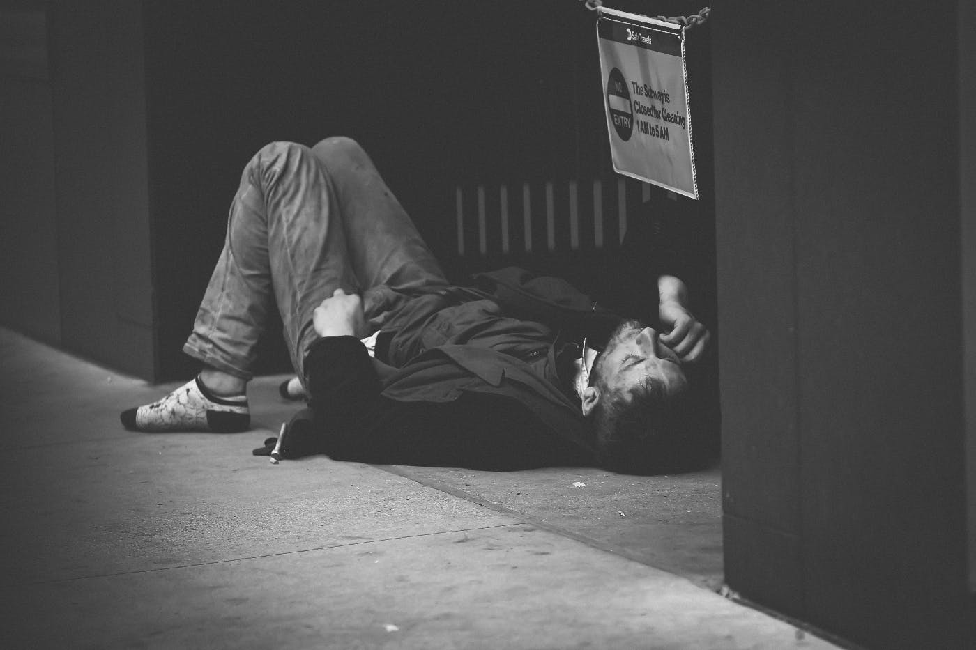 a man lying on the sidewalk in a doorway, strung out.