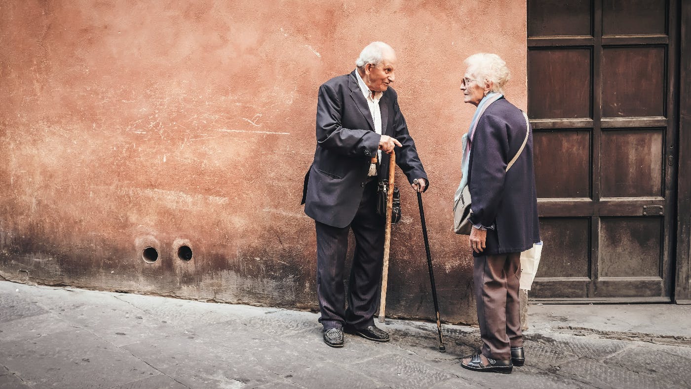 An older couple having a conversation on a street in Italy