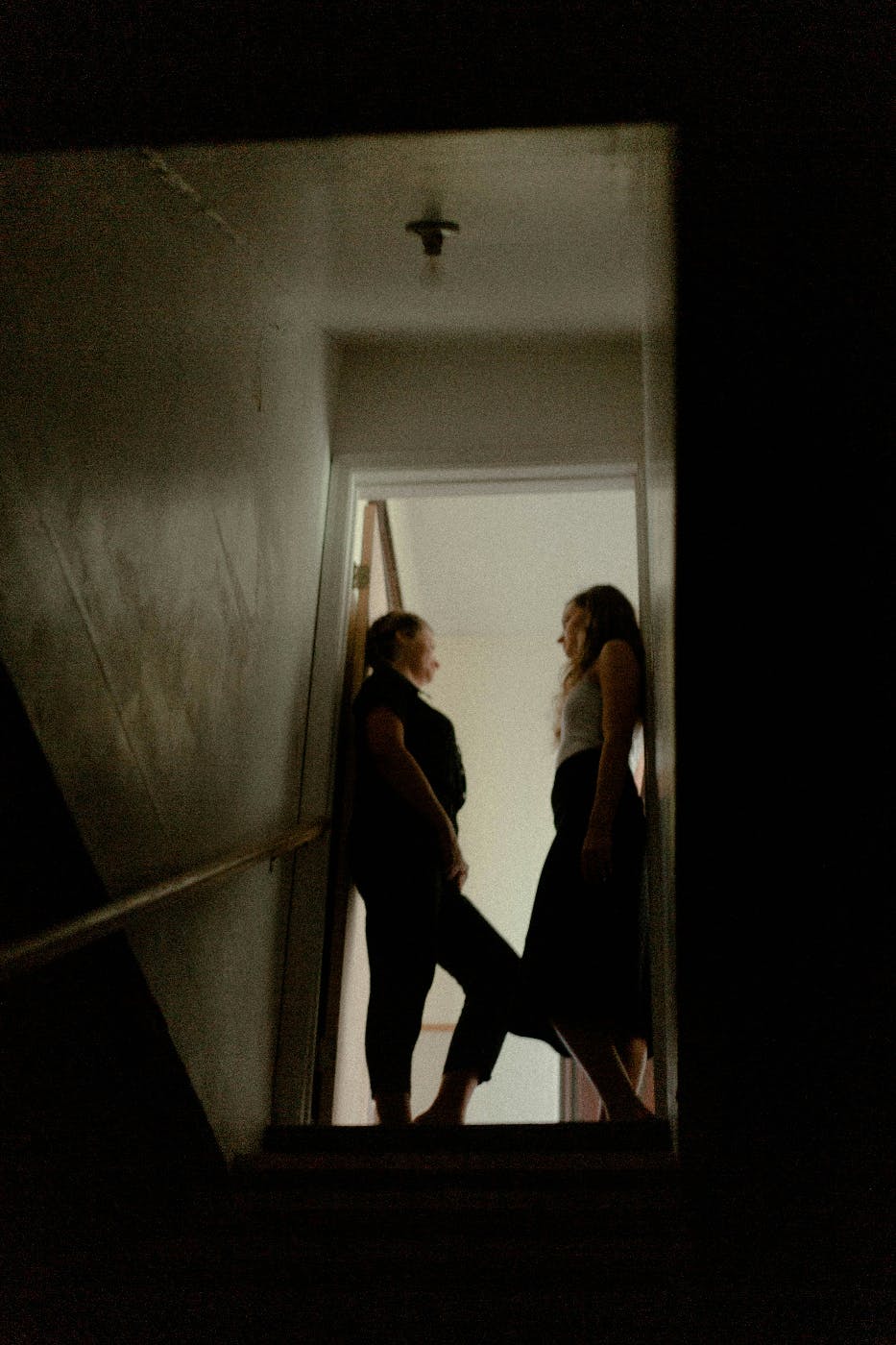 Two women having a conversation in a doorway at the top of a flight of stairs