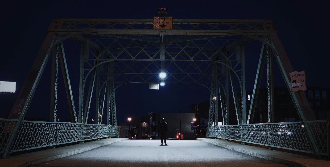 The silhouette of a person alone on a bridge