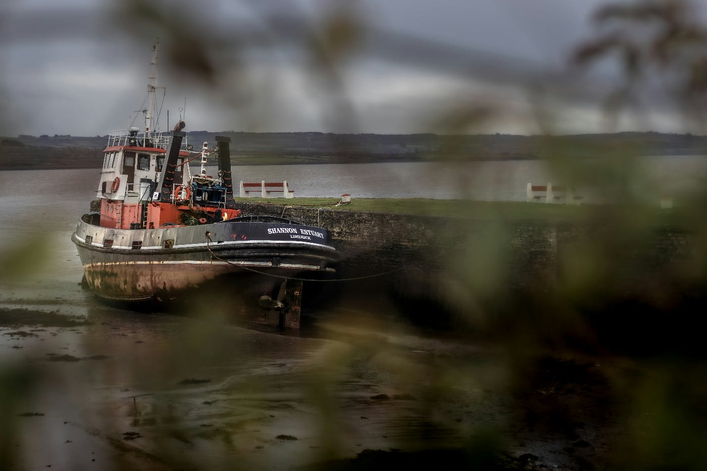 A boat in mud leaning against a jetty