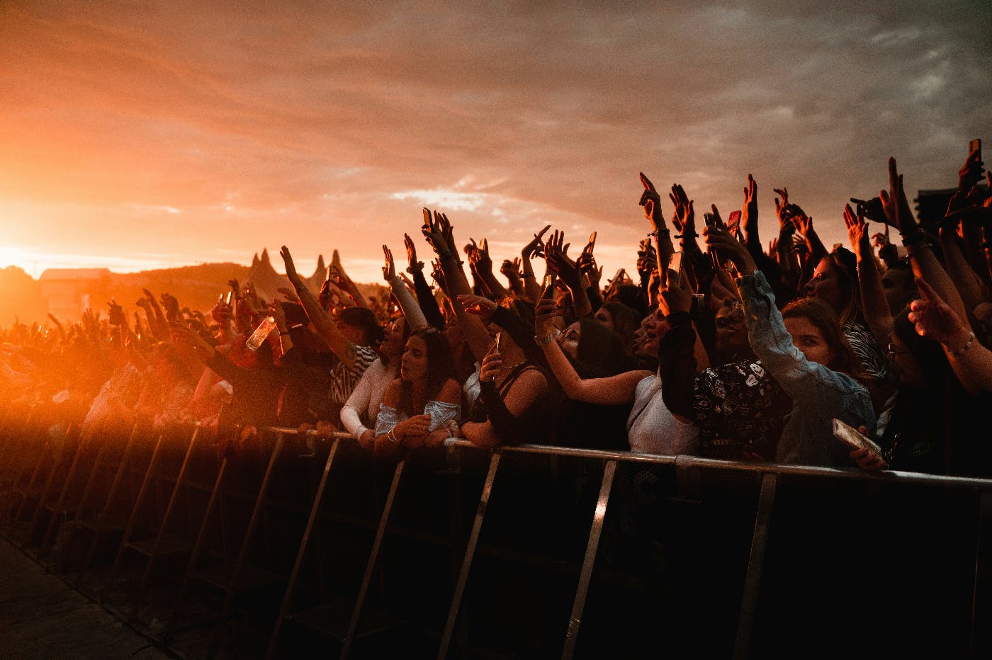 The sun setting on an outdoor audience, hands raised