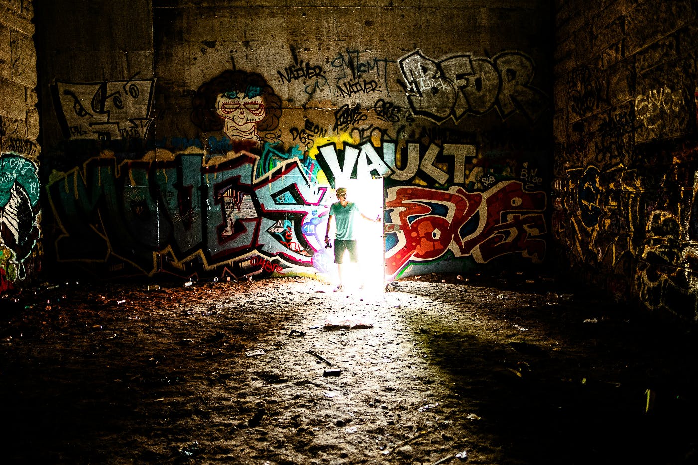 A man standing in the open doorway of a room with walls covered in graffiti