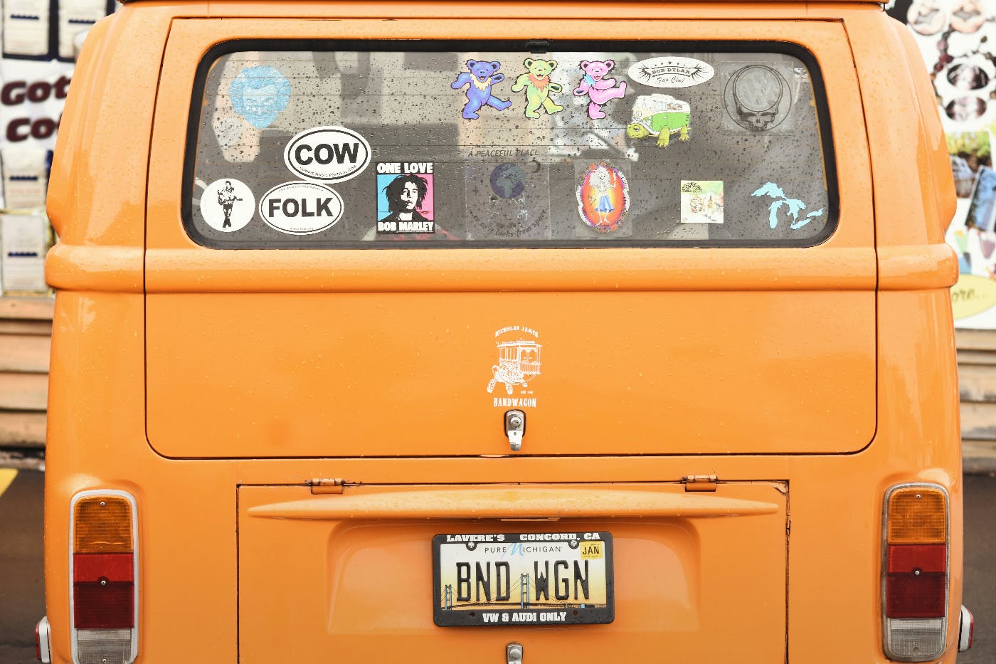 The back of an orange mini bus with personalized vanity plate and stickers