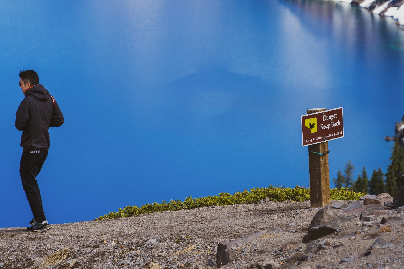 A sign reading Danger Keep back and a man who has passed the sign completely