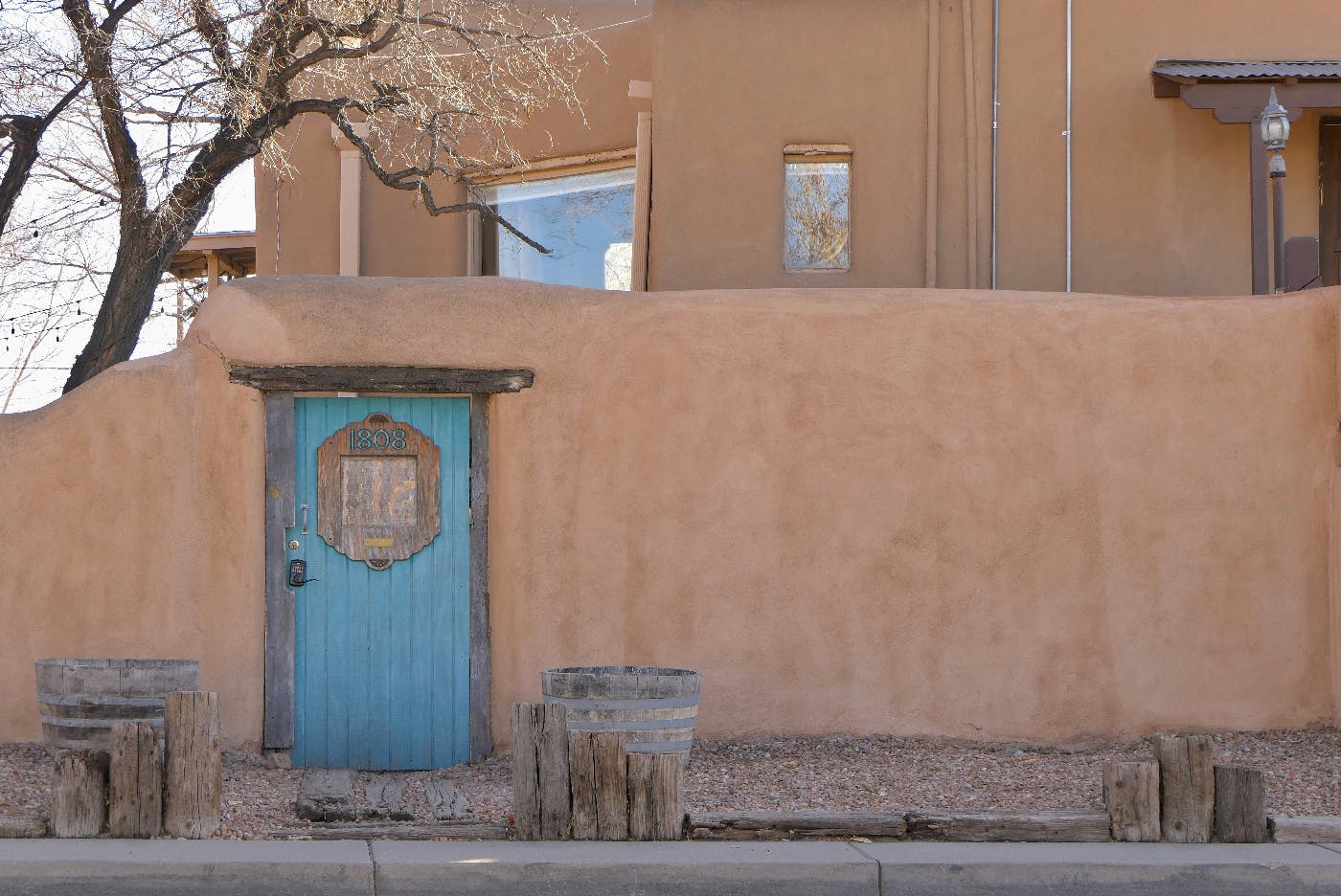 An adobe wall outside a house with a blue door