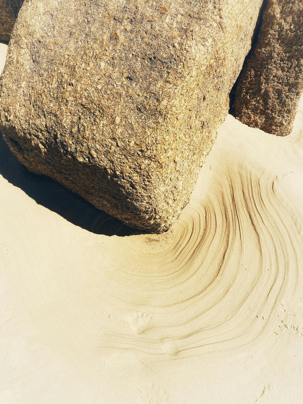 Erosion in the sand around a rock caused by wind